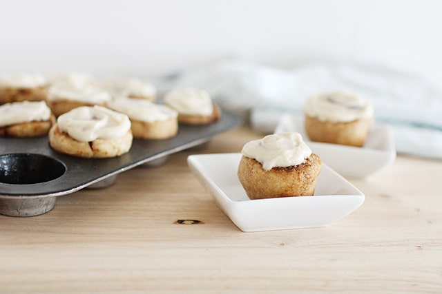 Mini cinnamon buns in a single serving muffin tin in a small white bowl on a wooden table