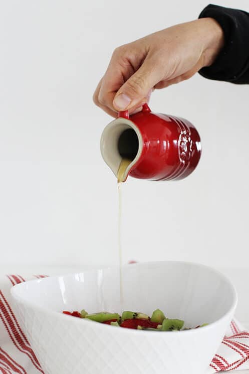 pouring sweet dressing onto fruit salad