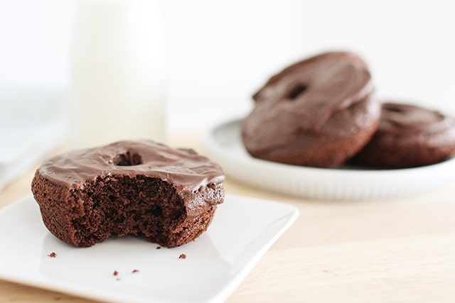 Make rich, chocolatey, homemade donuts right in your own kitchen! These donuts are baked, not fried, and even include a surprise ingredient that makes them a more balanced treat. homemade chocolate donut with bite taken out