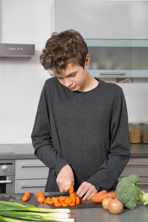 Teenage boy chopping vegetables