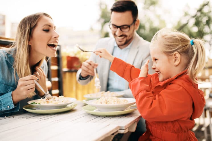 playful family eating pasta outside