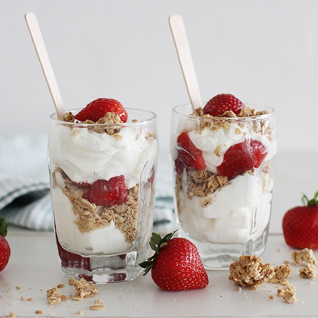 two glasses full of healthy yogurt parfait with berries and granola