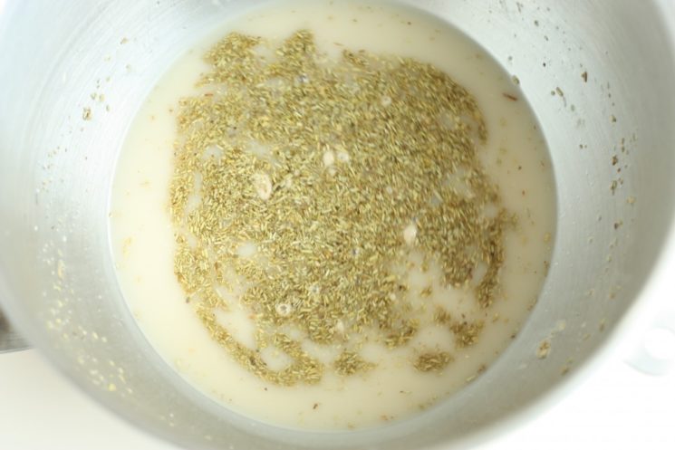 process shot of yeast, water and rosemary in a mixing bowl