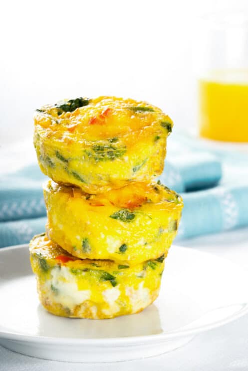 breakfast muffins with veggies and cheese stacked up