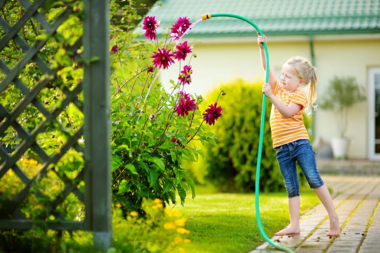 girl watering the flowers with a hose