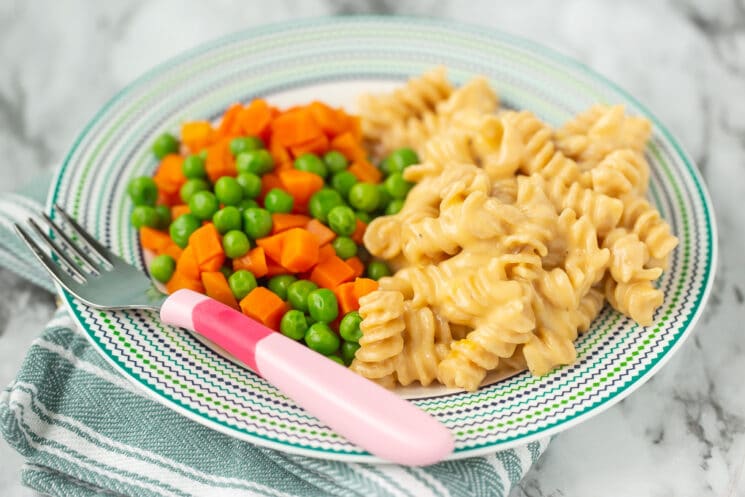 homemade mac and cheese with peas and carrots on a plate