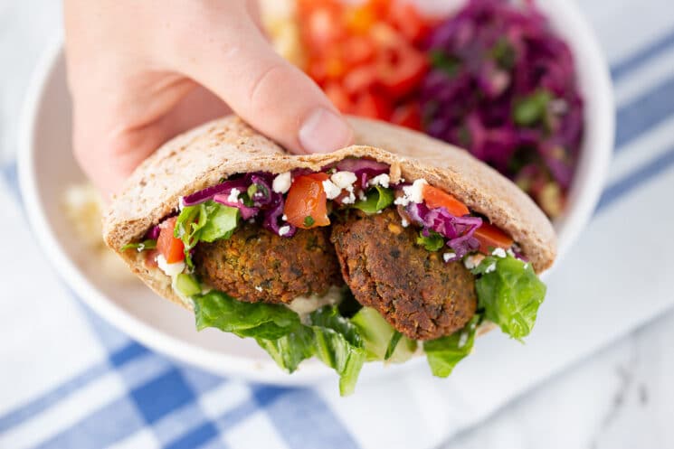 hand holding middle eastern pita pocket with falafel