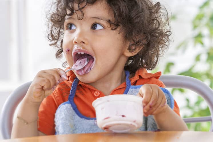 cute toddler eating yogurt with probiotics