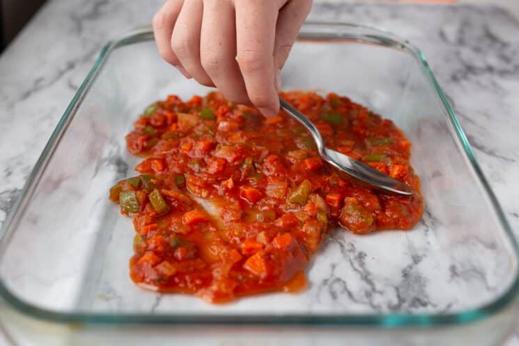 spreading sauce on the bottom of a pan for lasagna