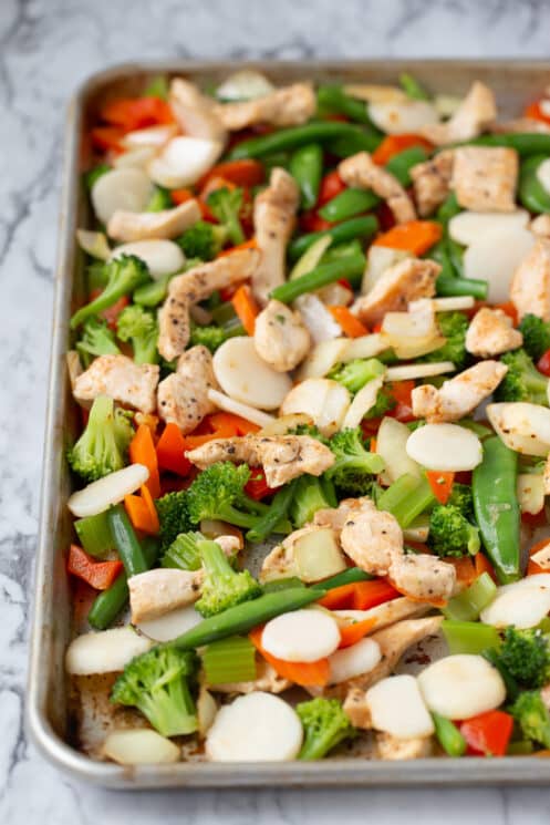 blanched veggies and cooked chicken freezing on a baking sheet