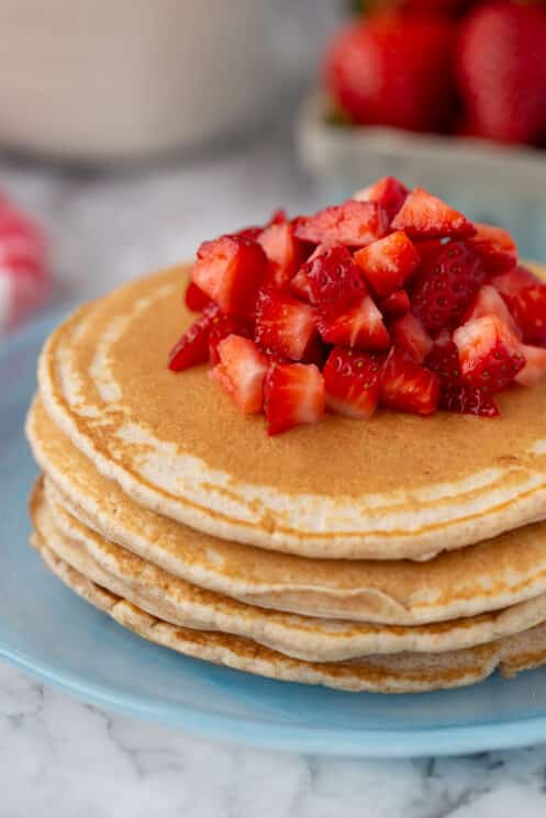 homemade pancakes with fresh strawberries on a blue plate