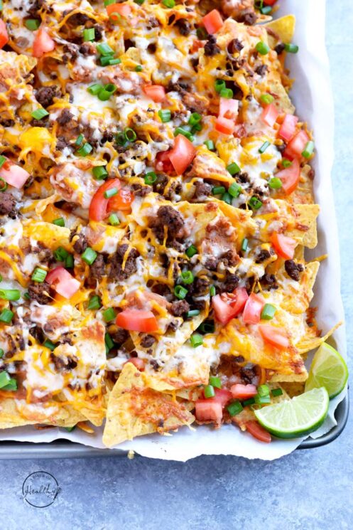 pan of crisp nachos with loads of fresh toppings like lime, scallions, and ground beef