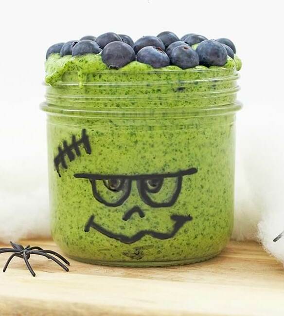 Groene smoothie in een glazen pot versierd om eruit te zien als frankenstein