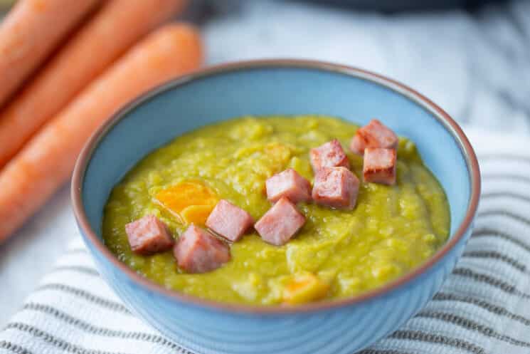 split pea soup in a blue bowl with ham cubes