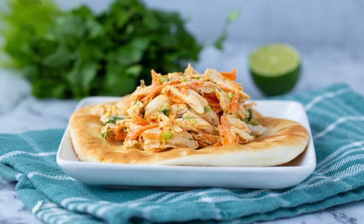 chicken salad with carrots, peppers, and yogurt dressing inside flatbread on a plate.