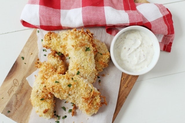 crispy chicken tenders on parchment paper with a creamy dip