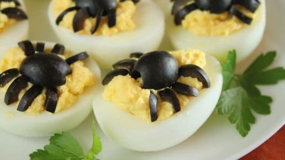 deviled eggs with black spiders made from olives