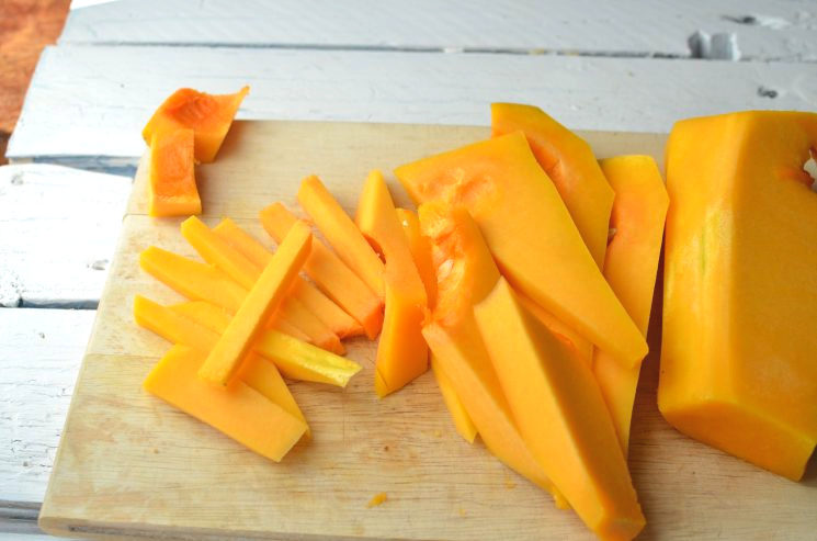 whole butternut squash cut into fry shapes on cutting board