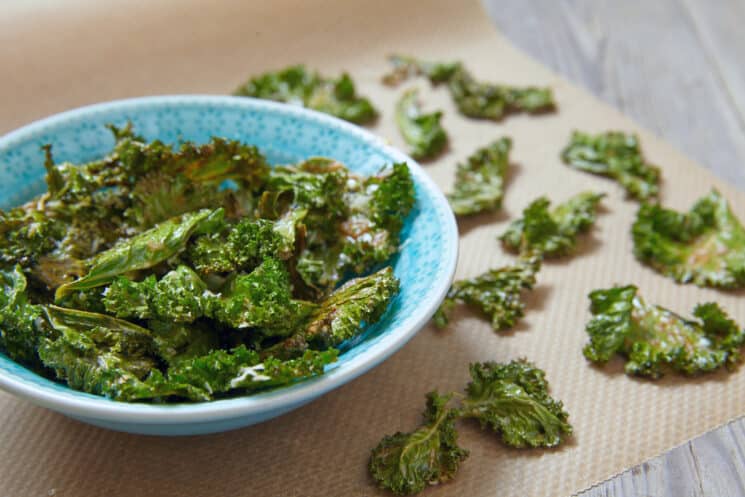 crispy kale chips in a blue bowl on a wooden table