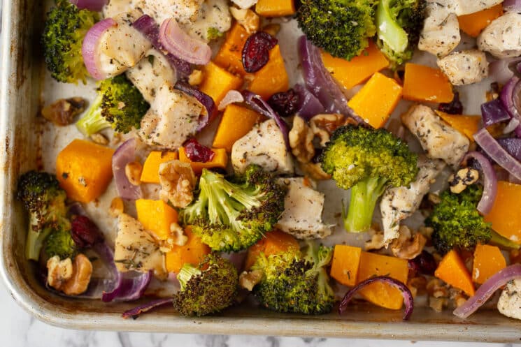 cooked sheet pan dinner with chicken, veggies, walnuts, and cranberries