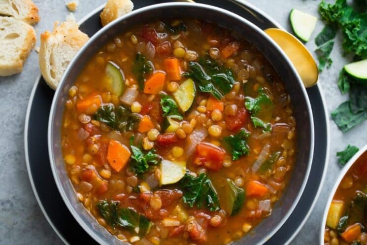 colorful lentil soup with veggies in a bowl with bread on the side