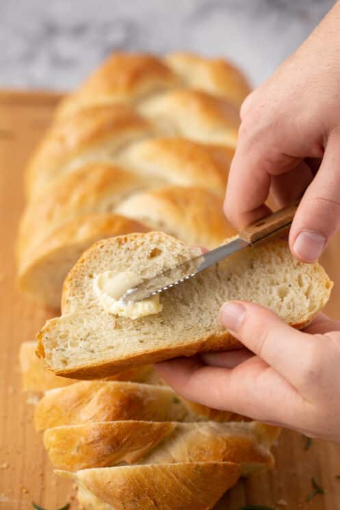 spreading butter on a slice of homemade braided bread