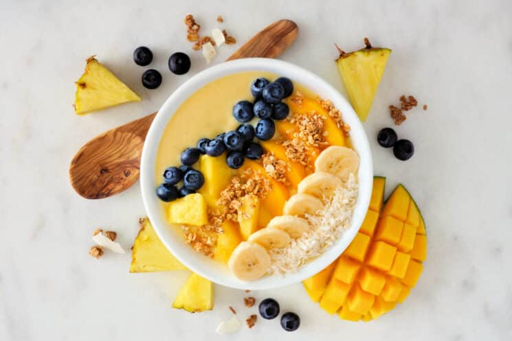 Mango smoothie bowl with blueberries, bananas, pineapple.