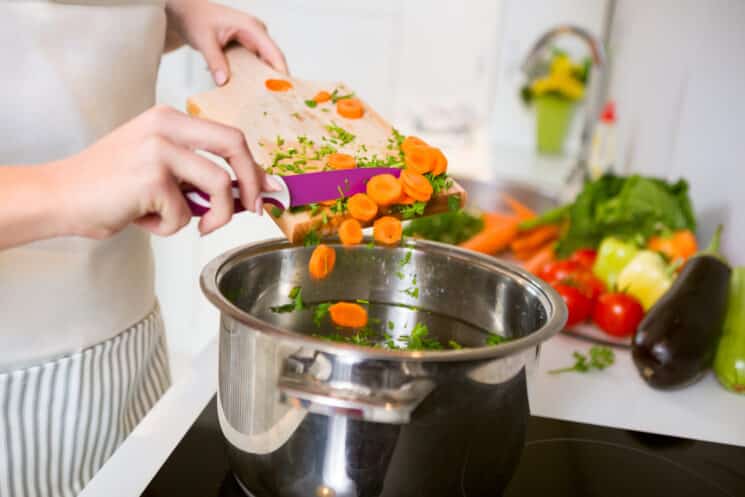 woman scraping veggies into a pot for cooking a healthy meal