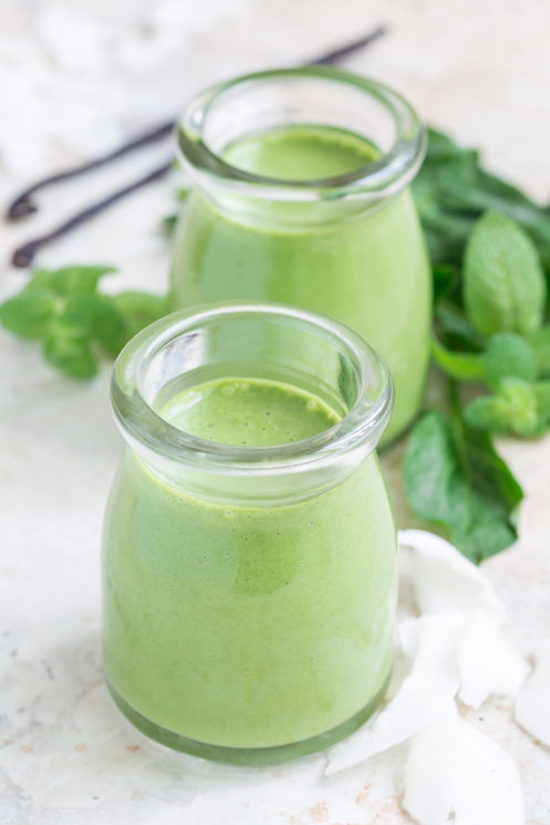 healthy green smoothies makeover of a shamrock shake in glass jars with spinach, mint and vanilla in the background