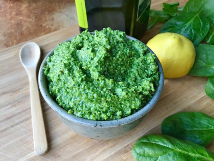 fresh spinach pesto in a bowl surrounded by ingredients