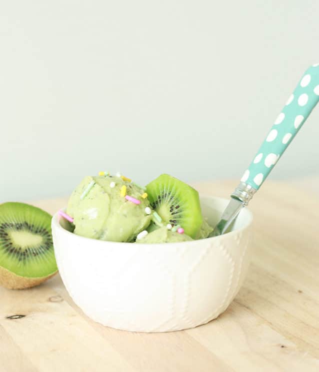 kiwi sorbet in a small ceramic bowl with a spoon and topped with colorful sprinkles.