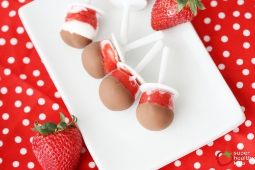 bright red and white swirled popsicles dipped in chocolate on a white plate, with polka dot placemat underneath