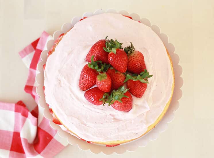 overhead view of a vanilla cake with whole strawberries on top