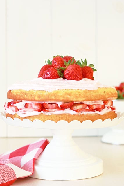 Double layer vanilla cake with sliced strawberries on a cake stand