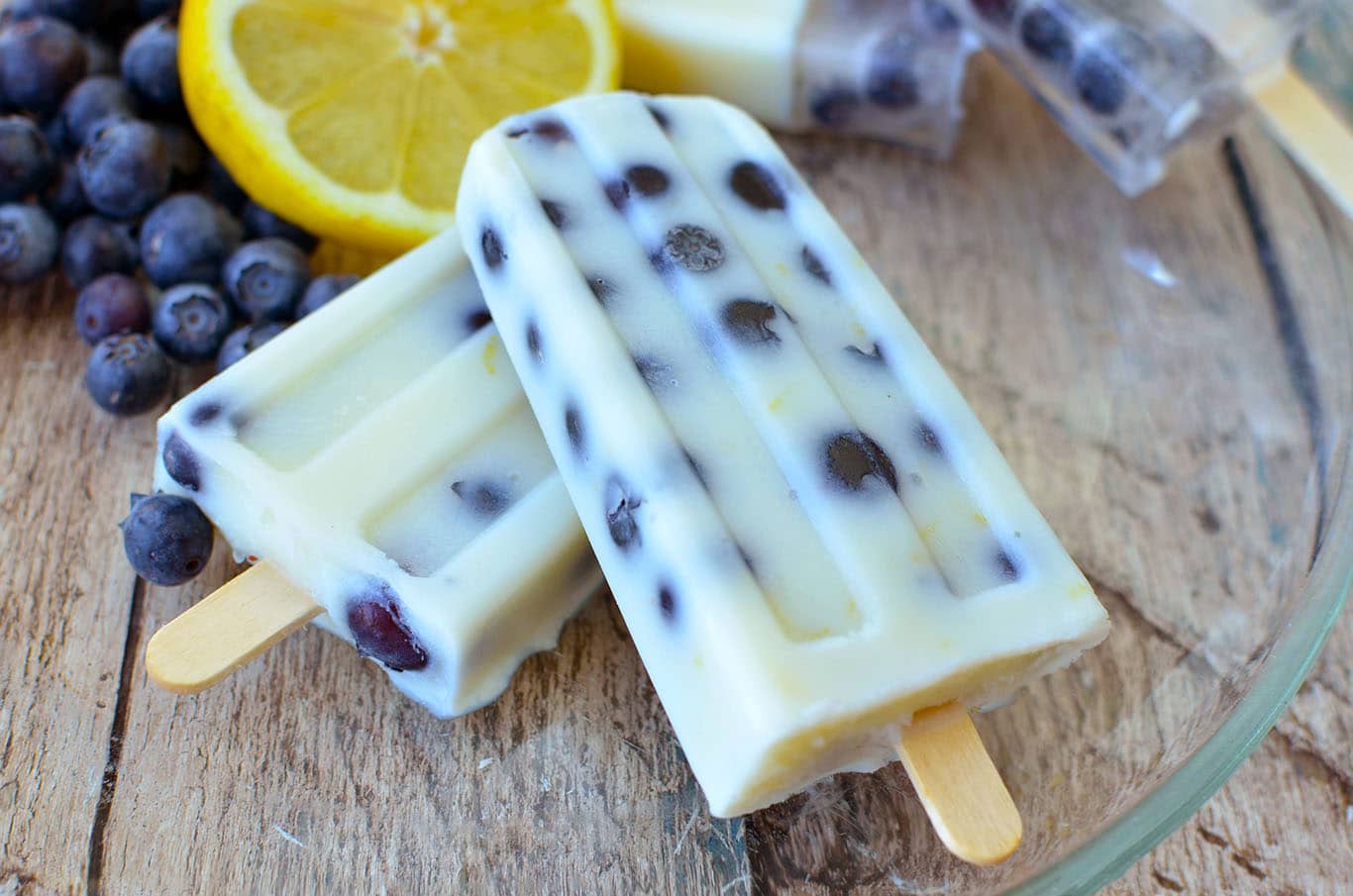 Blueberry Lemon Pudding pops on a plate with blueberries and lemons