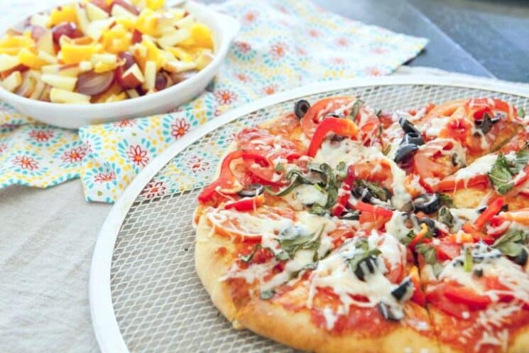 grilled pizza on an outdoor table next to fruit salad