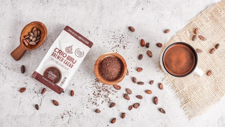 Crio Bru package with cacao beans spread around it and ground cacao in a bowl