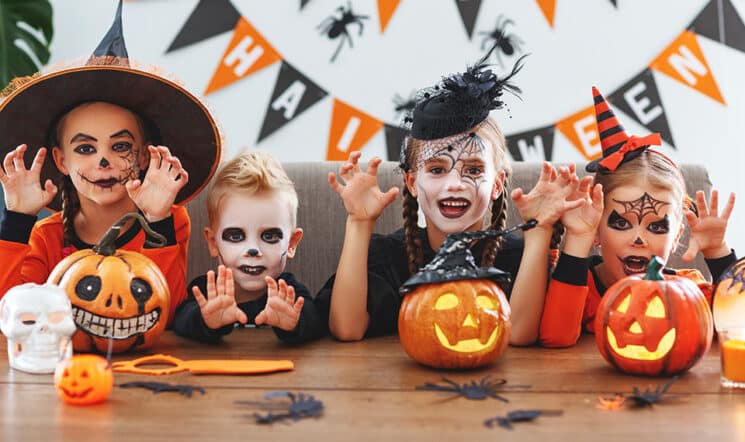 a group of children in halloween costumes with pumpkins in the home