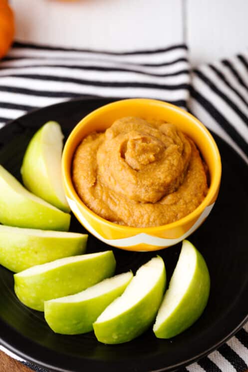 pumpkin spice dip close up photo with green apples on a black plate