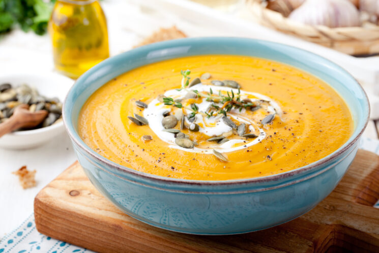 pumpkin soup topped with pumpkin seeds in a blue bowl