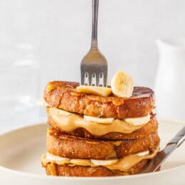 stack of peanut butter banana french toast on a plate with a fork in the stack