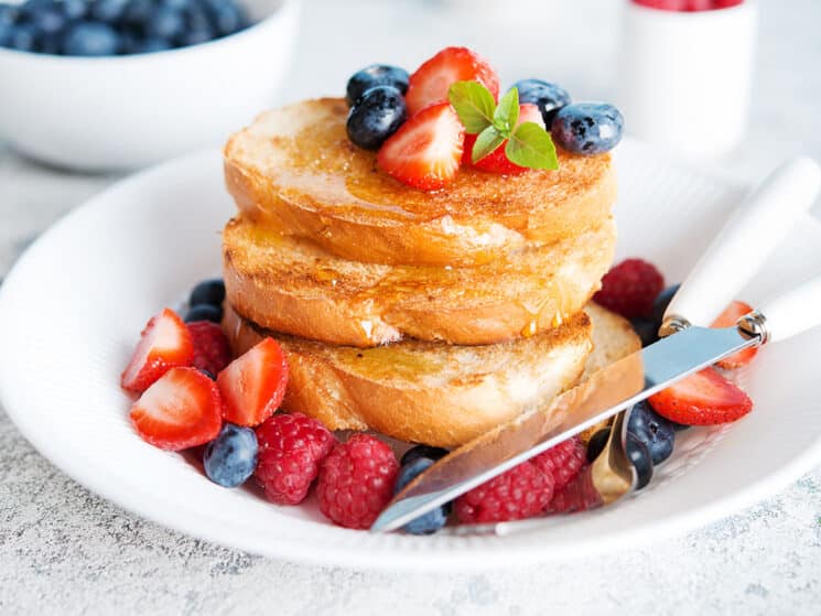 basic french toast topped with strawberries, blueberries and raspberries on a white plate