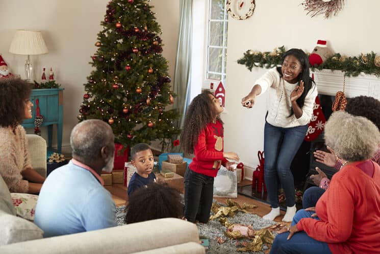 Multi-generation family play charades while they celebrate Christmas together at home