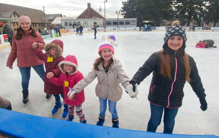 a family of girls holding hands while ice skating
