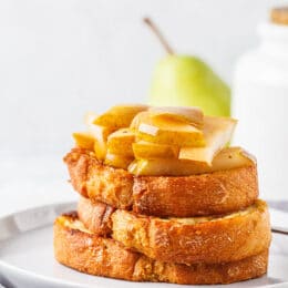 Baked french toast with caramelized pear and syrup on a gray background.