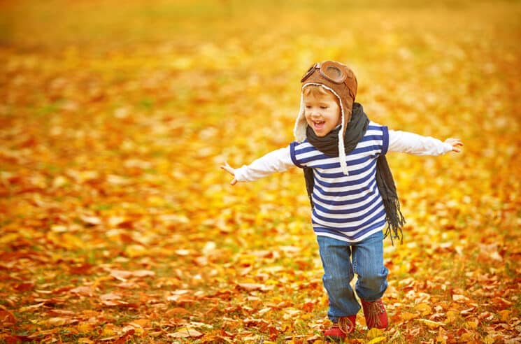 happy child playing pilot aviator and dreams outdoors in autumn