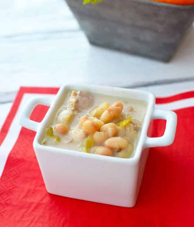 white bean chicken chili in a square white dish with a red placement underneath
