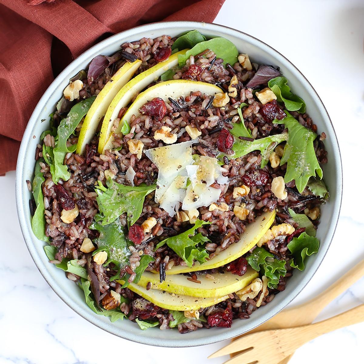 wild rice salad with pear, cranberries, walnuts and parmesan cheese in a bowl