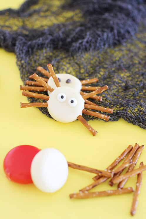 spider bites healthy halloween snack made of baby bell cheese and pretzel sticks for legs