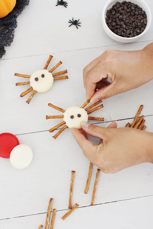 spider bites healthy halloween snack made of baby bell cheese and pretzel sticks for legs